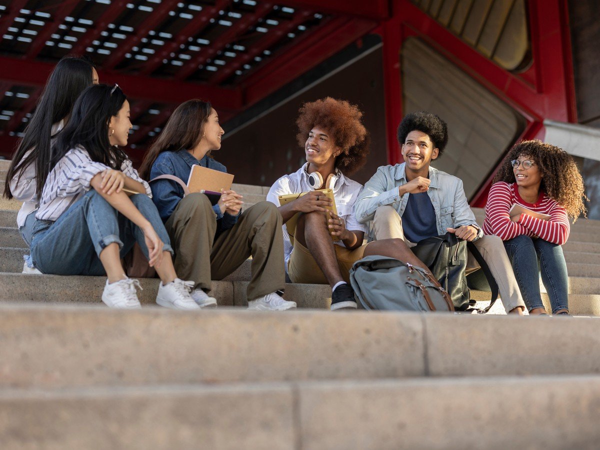 A group of diverse students sitting together on the steps of a building