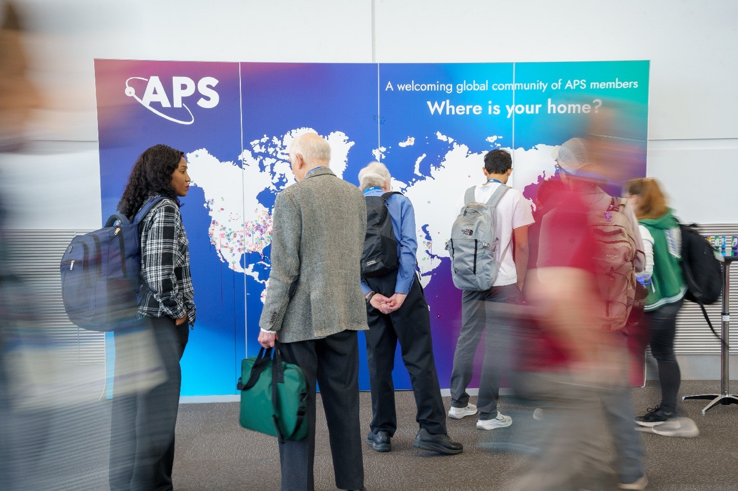 A blur of people interacting with a colorful “Where is your home?” map.