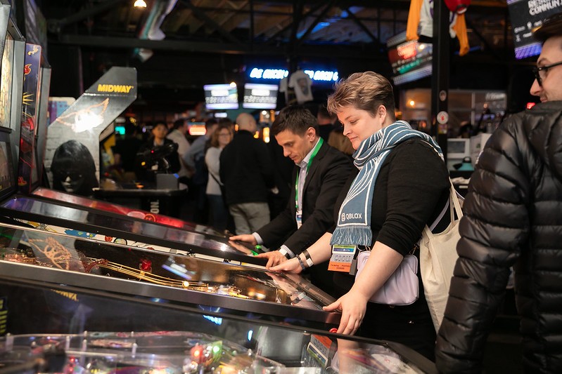 Potanina plays pinball in a crowded room at the March Meeting in 2024.