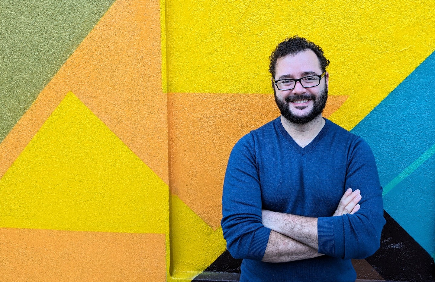 Brian Casas sitting in front of a colorfully abstract wall
