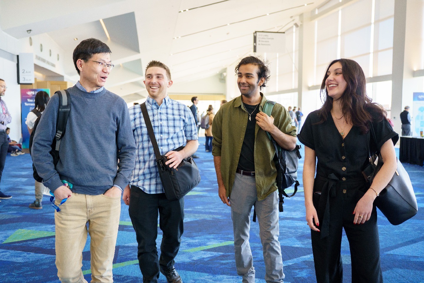 Four meeting attendees chat as they walk through a large walkway