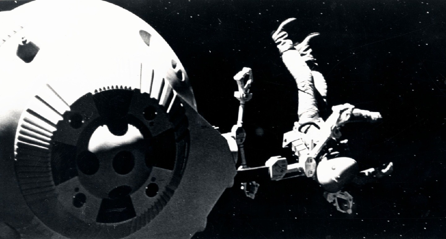 An astronaut in a spacesuit floats in space, with a spherical spacecraft visible behind him, in a scene from “2001: A Space Odyssey.”