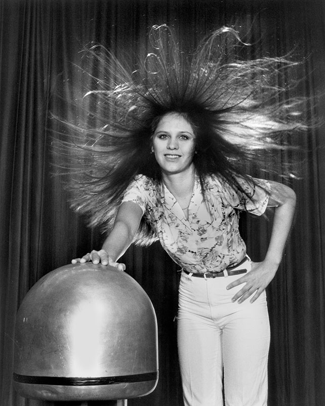 A woman touches the terminal of a Van de Graaff generator at Oak Ridge