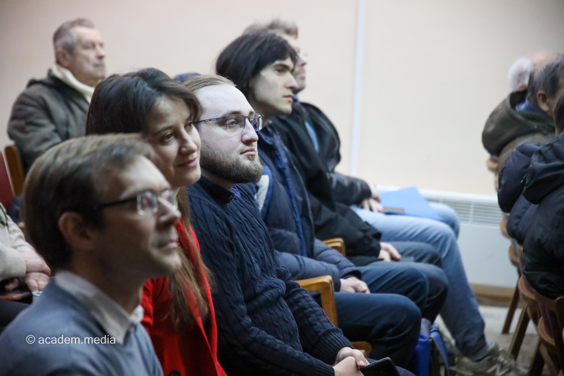 Attendees seated in a row, listening to a presentation off-camera.
