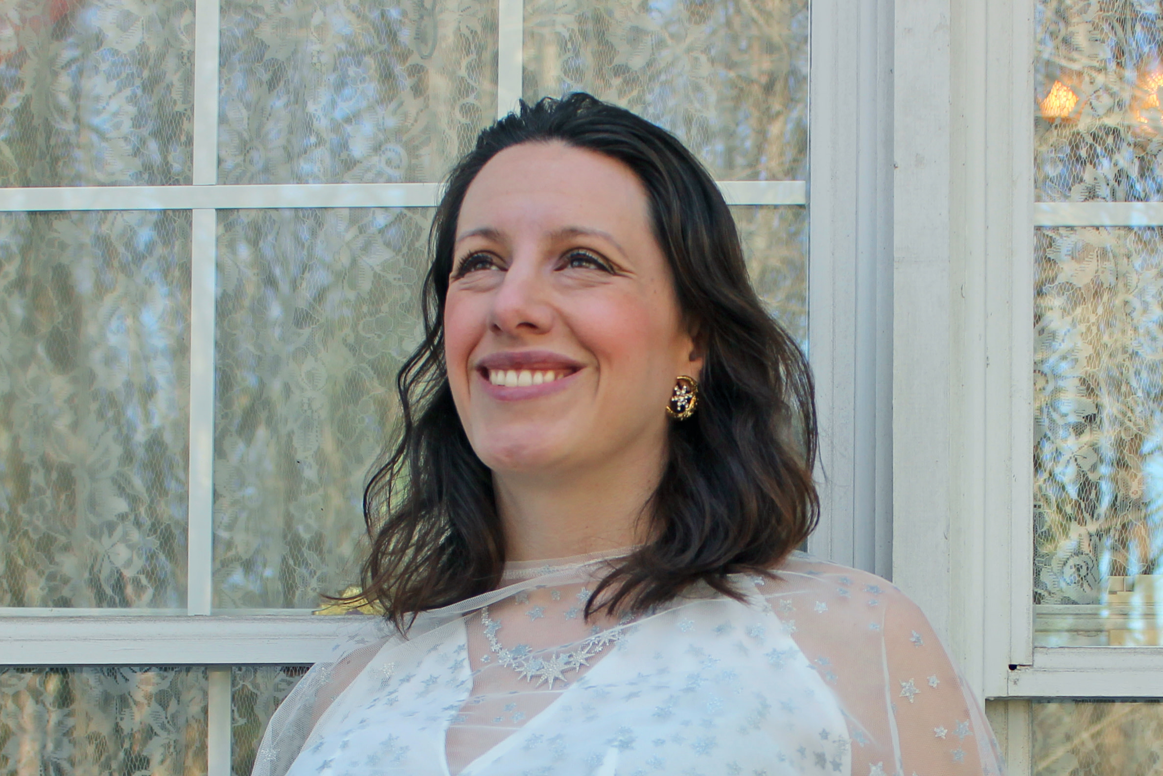 A headshot of Laura Forczyk, who is smiling and looking into the distance with windows visible behind her.